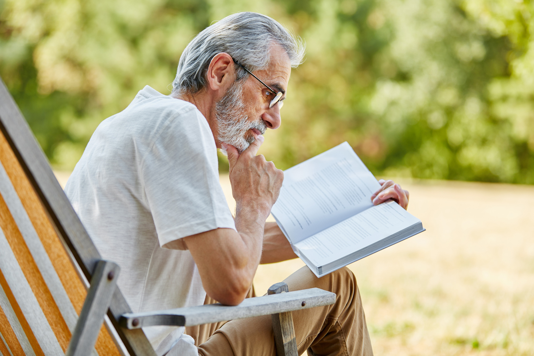 Old Man Reading a Book on a Deck Chair